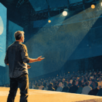 Editorial illustration of a speaker presenting on stage to a large audience at a technology conference.
